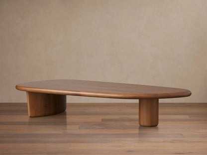 Front view of the solid oak Akiro Coffee Table, featuring a rounded oval top and sturdy base, styled with books and a vase.