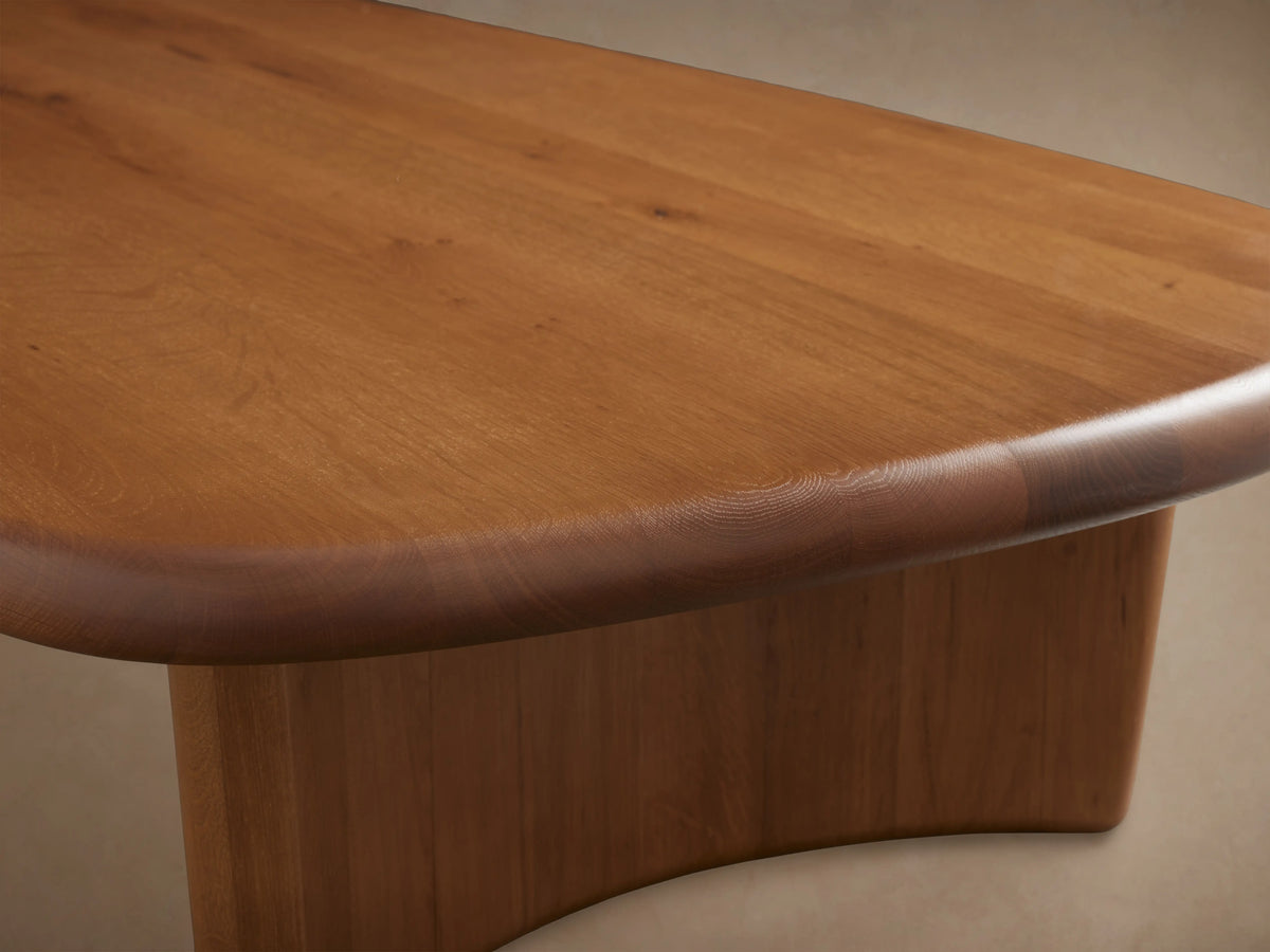Akiro Coffee Table made from solid oak wood with a unique asymmetrical shape, rounded edges, and two cylindrical legs.