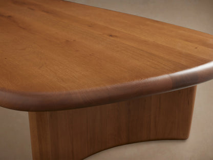 Akiro Coffee Table made from solid oak wood with a unique asymmetrical shape, rounded edges, and two cylindrical legs.
