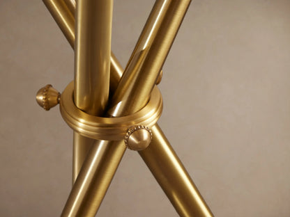 Albie Martini Table featuring a circular brass top with polished edges, supported by sleek, intersecting brass legs with decorative knobs.