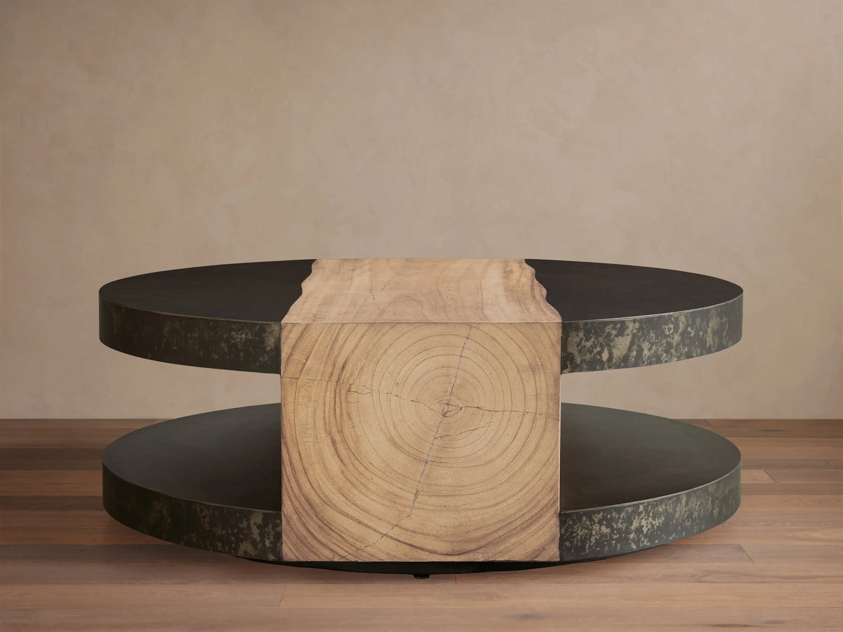 Front view of the Almeria Round Coffee Table. Dark oxidized steel rings frame a central light brown guanacaste wood block with grain.