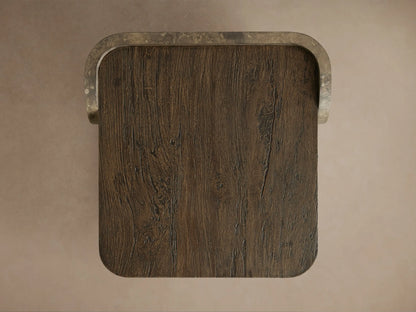 Close-up of Alvaro End Table's dark wood top with visible grain, meeting a curved, weathered aluminum side panel with rich patina.