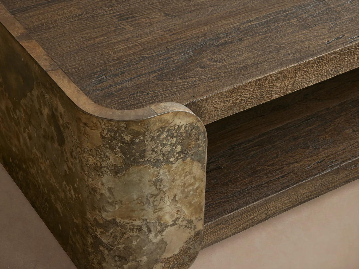 Alvaro Coffee Table, two-tiered, dark textured wood shelves with curved, mottled greenish-grey weathered aluminum supports.