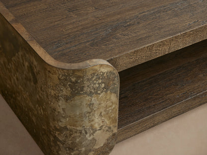 Alvaro Coffee Table, two-tiered, dark textured wood shelves with curved, mottled greenish-grey weathered aluminum supports.