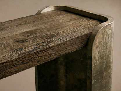 Alvaro Console Table: Rectangular table with dark, rustic spalted wood top and bottom shelves, and curved, weathered aluminum sides.