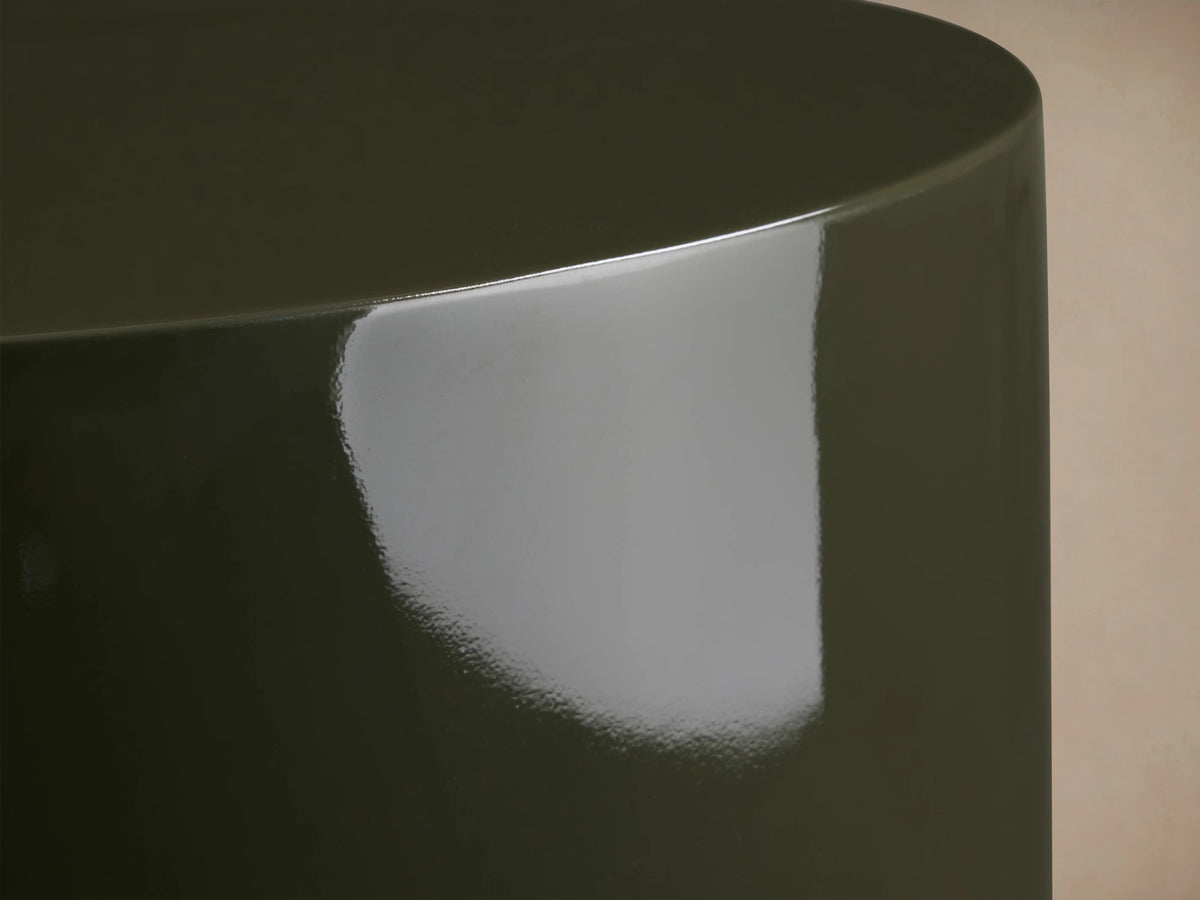 Alwyn Lacquer Stool in dark green finish, glossy cylindrical shape with a slightly wider base, placed on wooden floor.