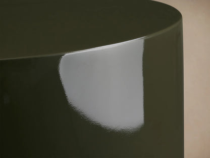 Alwyn Lacquer Stool in dark green finish, glossy cylindrical shape with a slightly wider base, placed on wooden floor.