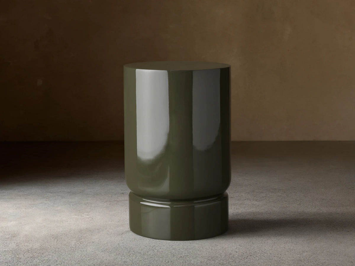 Alwyn Lacquer Stool in dark green finish, glossy cylindrical shape with a slightly wider base, placed on wooden floor.