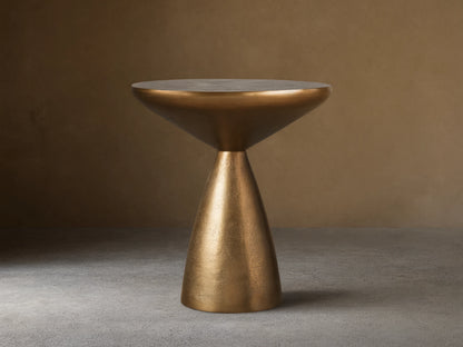 Amina End Table in polished bronze finish, featuring an inverted cone top and tapered base, placed on wood floor.