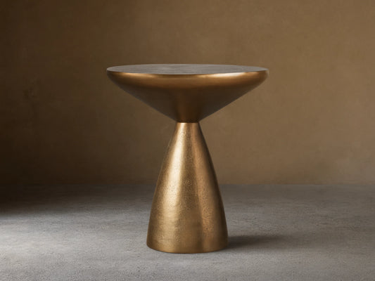 Amina End Table in polished bronze finish, featuring an inverted cone top and tapered base, placed on wood floor.