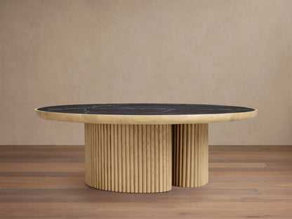 Astor Round Coffee Table with ribbed oak-wrapped wood veneer base and black natural marble top, on wooden floor.