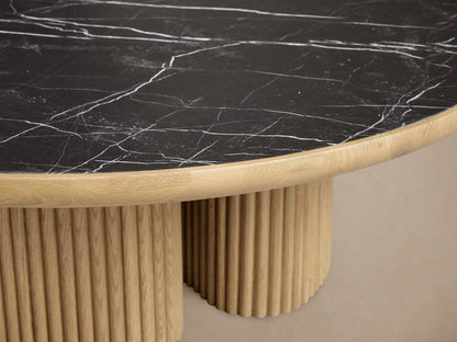Astor Round Coffee Table with a black marble top and dual cylindrical oak bases, set against a neutral background.