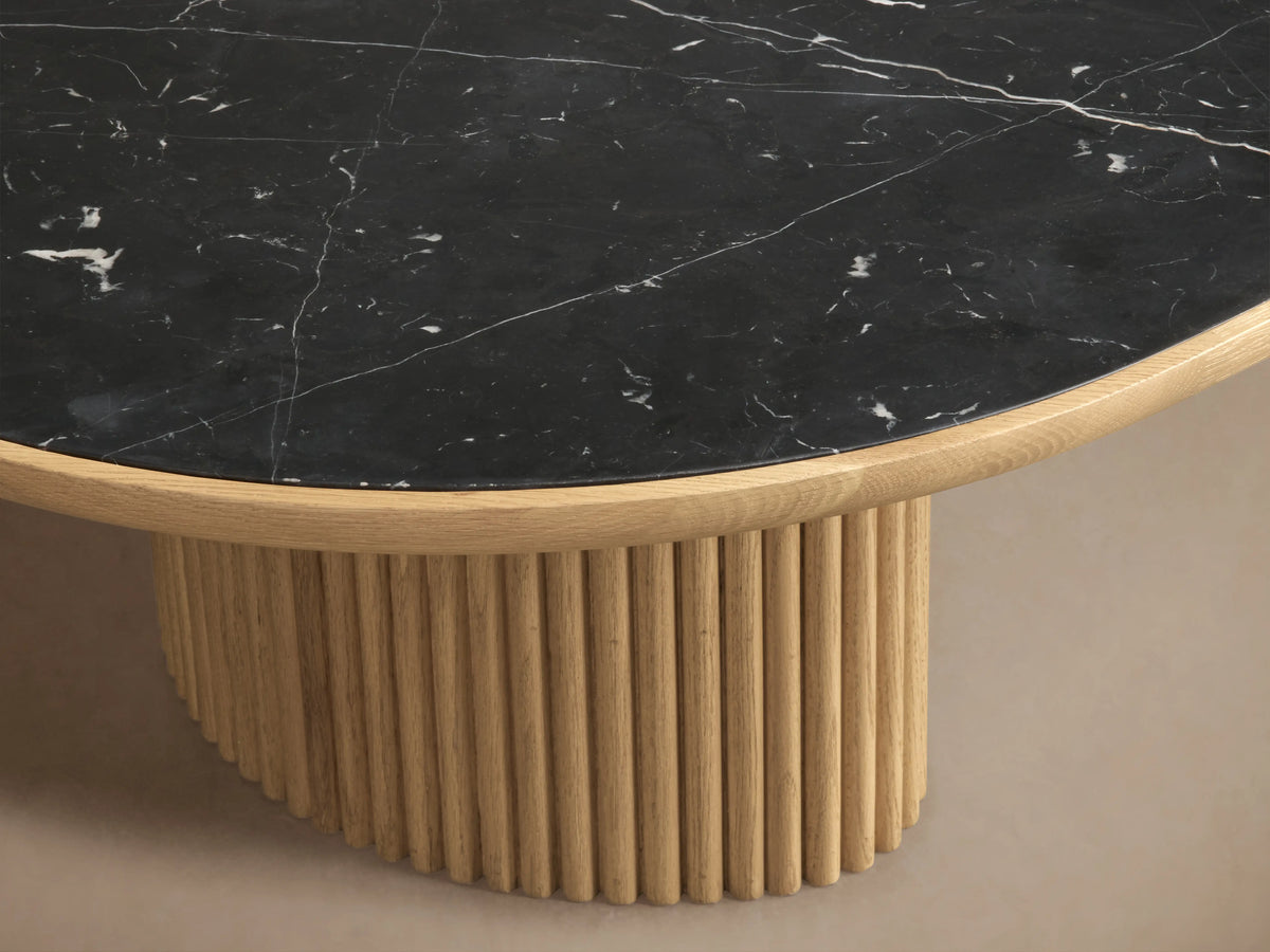 Astor Coffee Table with an oval marble tabletop and two cylindrical, reed-wrapped oak bases on a wooden floor.