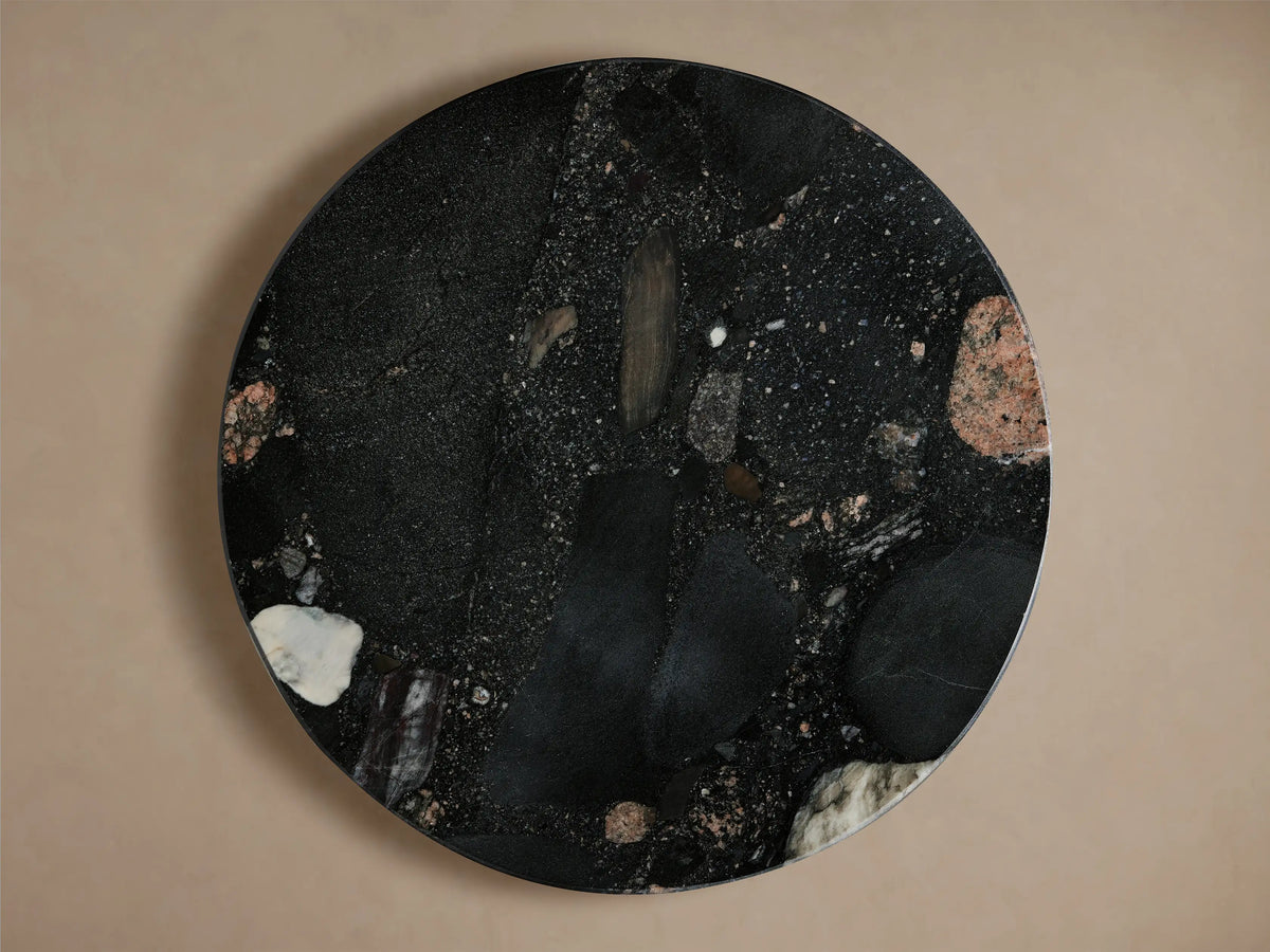 Close-up of Beaufort Martini Table's round black composite top with varied natural stone inclusions in red, white, gray.