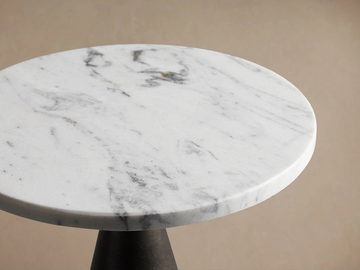 Beaufort Martini Table, featuring a round white marble top atop a conical dark graphite base, on a wood floor.