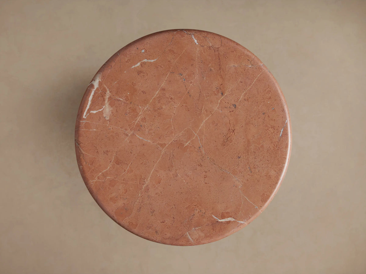 Close-up of Brecken Martini Table. Round, reddish-brown marble top with light veins, unique gold pattern, and tapered base.