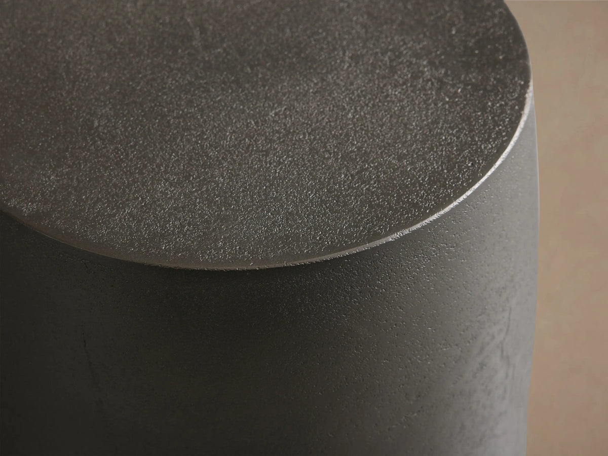 Dark gray Hammered Drum End Table with an antiqued metallic finish, standing on a wood floor against a neutral wall.