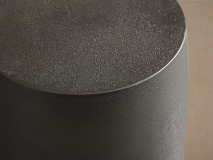 Dark gray Hammered Drum End Table with an antiqued metallic finish, standing on a wood floor against a neutral wall.