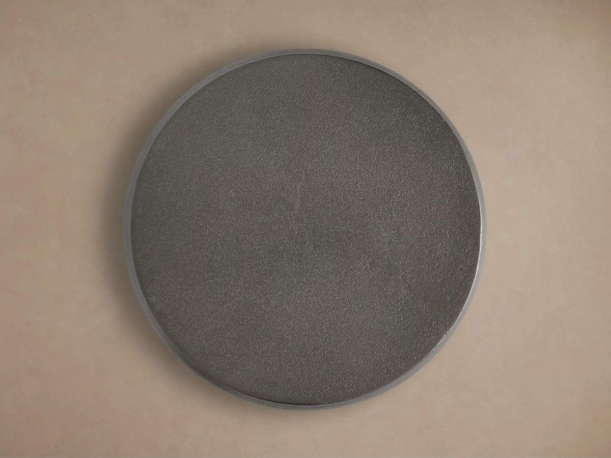 Close-up of a dark, cylindrical Hammered Drum End Table showing its textured, antiqued metallic surface and top edge.