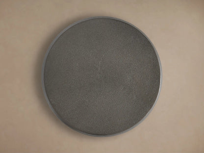 Close-up of a dark, cylindrical Hammered Drum End Table showing its textured, antiqued metallic surface and top edge.