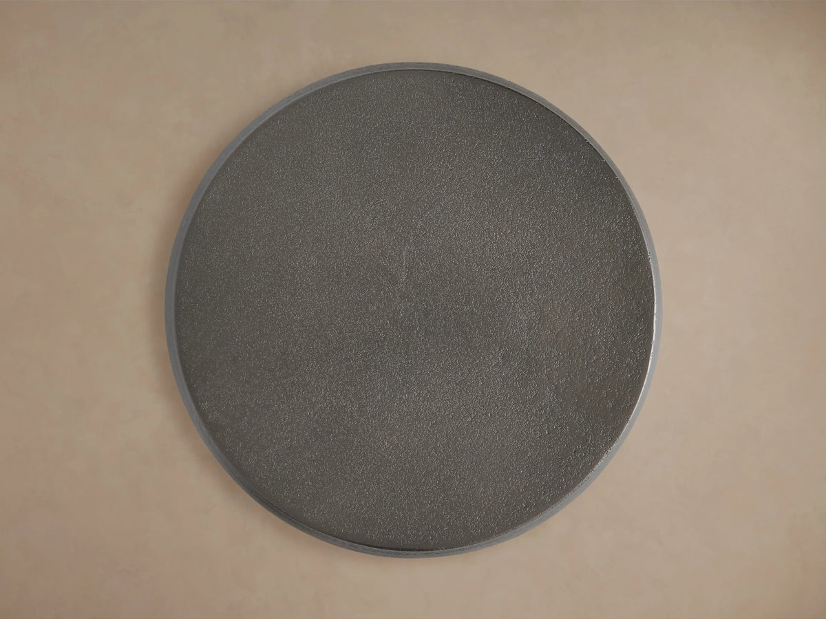 Hammered Drum End Table made of dark artisan-cast aluminum with a smooth, curved surface and antiqued finish on a wooden floor.