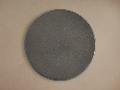 Hammered Drum End Table made of dark artisan-cast aluminum with a smooth, curved surface and antiqued finish on a wooden floor.