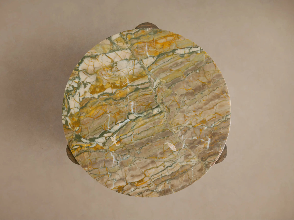 Close-up of Bellino Martini Table. Round marble top with yellow, green, white veins, nestled in a carved, textured oak base.