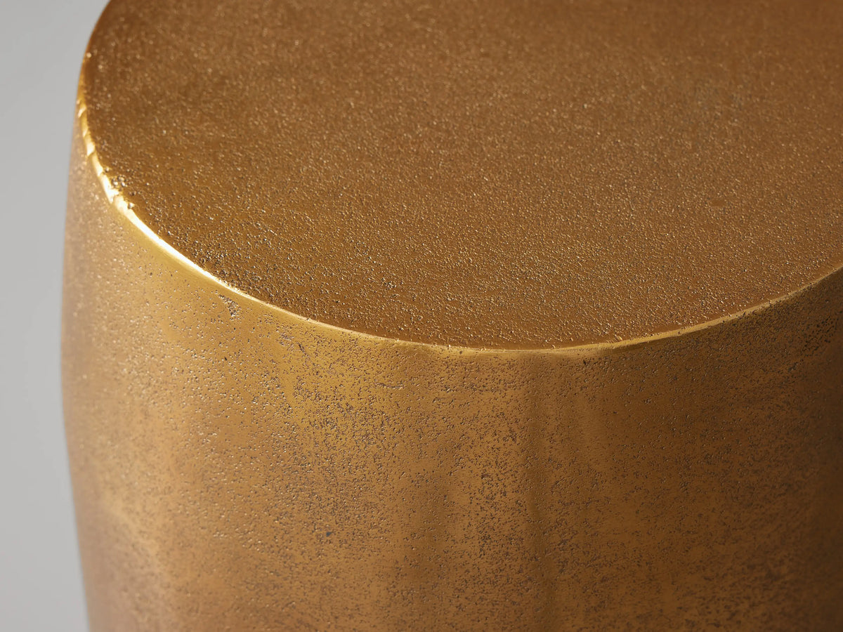 Hammered Drum End Table with an antiqued metallic gold finish and hand-pounded texture, standing upright against a grey background.