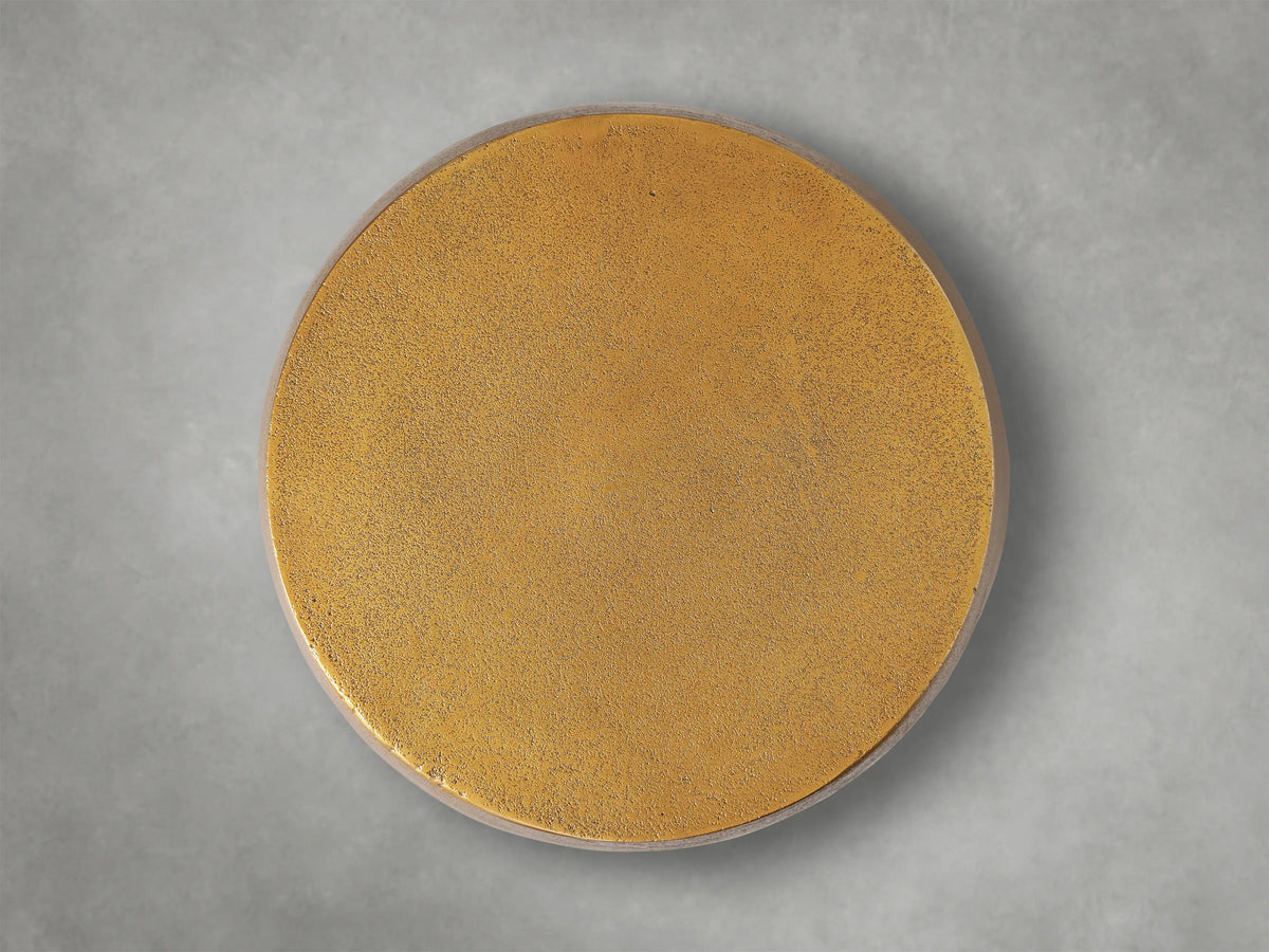 Close-up of a Hammered Drum End Table, showing its textured, antiqued metallic gold top edge and side with hand-pounded detailing.