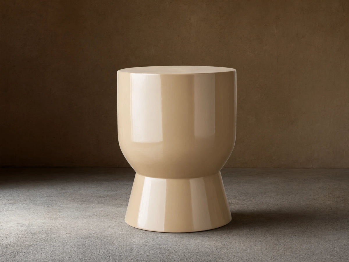 Beige Bridgers Lacquer Stool with a shiny, high-gloss finish. Features a cylindrical top and flared base on a wooden floor.