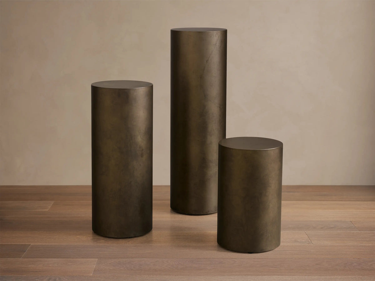 Close-up of the Bronze Bruna Pedestal, showing its cylindrical shape and rich, weathered metal patina.
