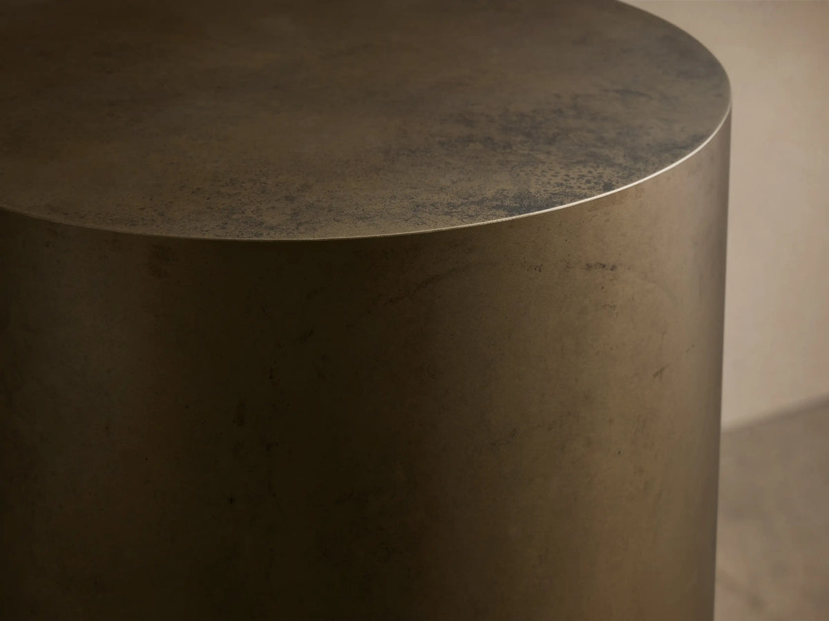 Close-up of the distressed bronze cylindrical object, showing its textured top surface and side from a slight angle.
