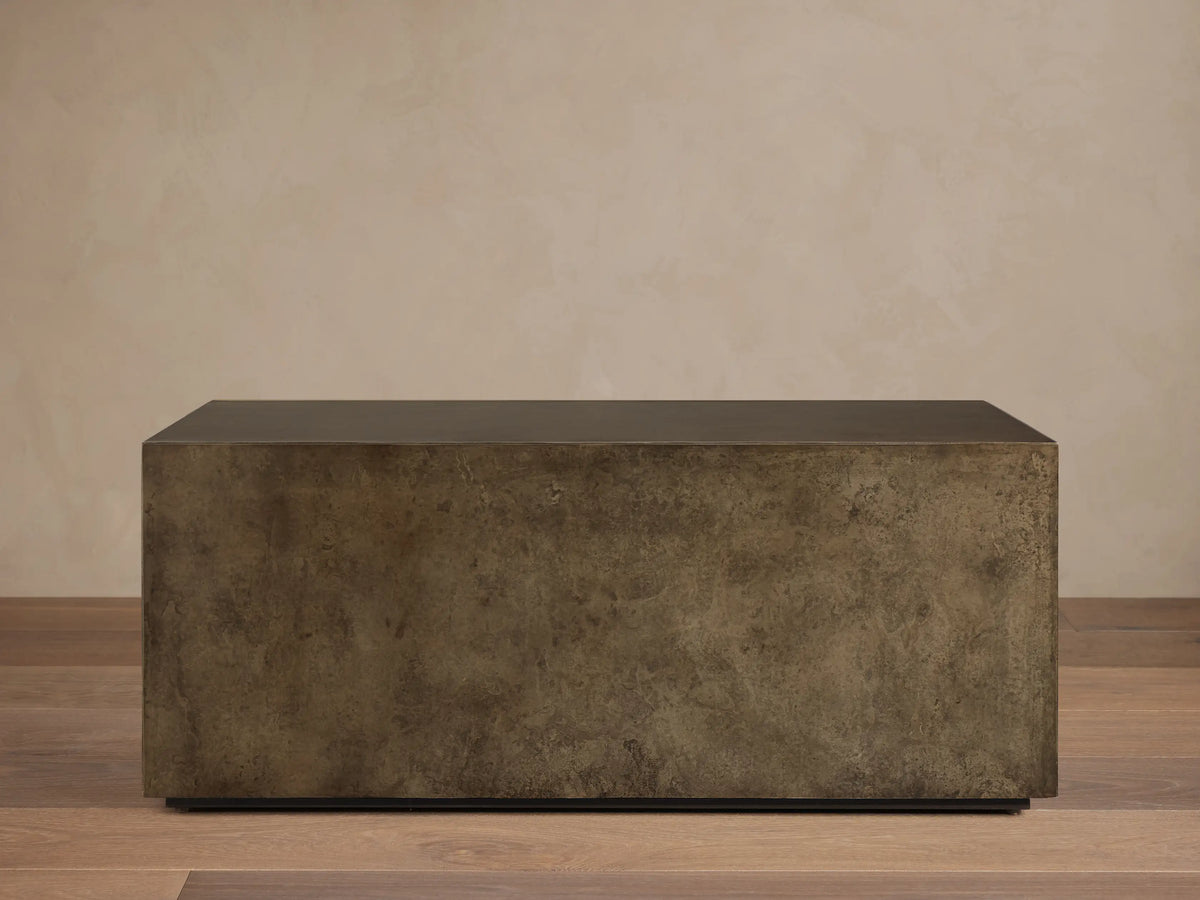 Front view of an aged bronze-toned rectangular coffee table, showing its dark top and mottled, textured sides.