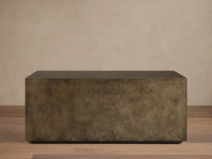 Front view of an aged bronze-toned rectangular coffee table, showing its dark top and mottled, textured sides.
