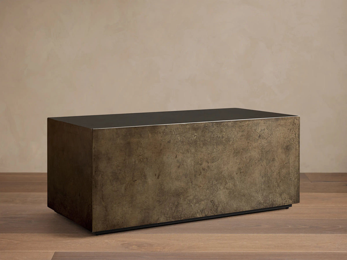 Front view of an aged bronze-toned rectangular coffee table, showing its dark top and mottled, textured sides.