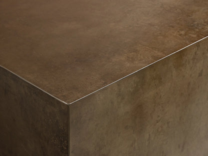 Angled view of a rectangular coffee table featuring a distressed bronze body, a dark top, and a subtle metallic silver trim.