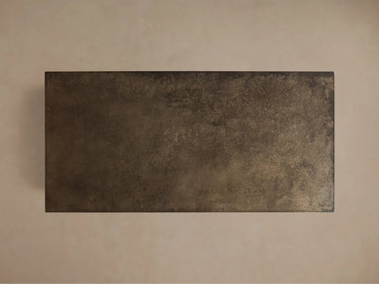 Close-up of a dark bronze, distressed metallic-looking surface with a mottled texture and sharp corner.