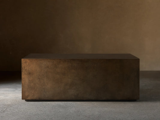 Front view of an aged bronze-toned rectangular coffee table, showing its dark top and mottled, textured sides.