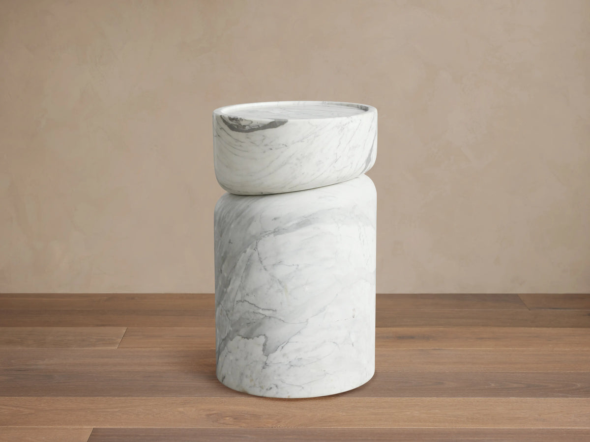Mayer Martini Table with round, white stone tabletop featuring natural veining patterns and subtle carved edging, on beige background.