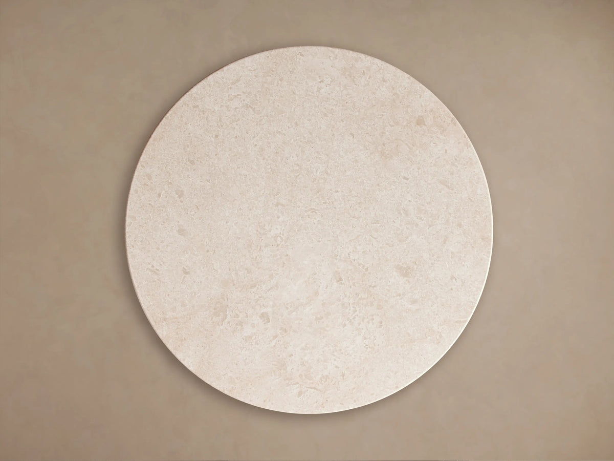 Caden Round Coffee Table close-up. Cream stone top with natural patterns and a dark walnut wood veneer base with an antique bronze plinth.