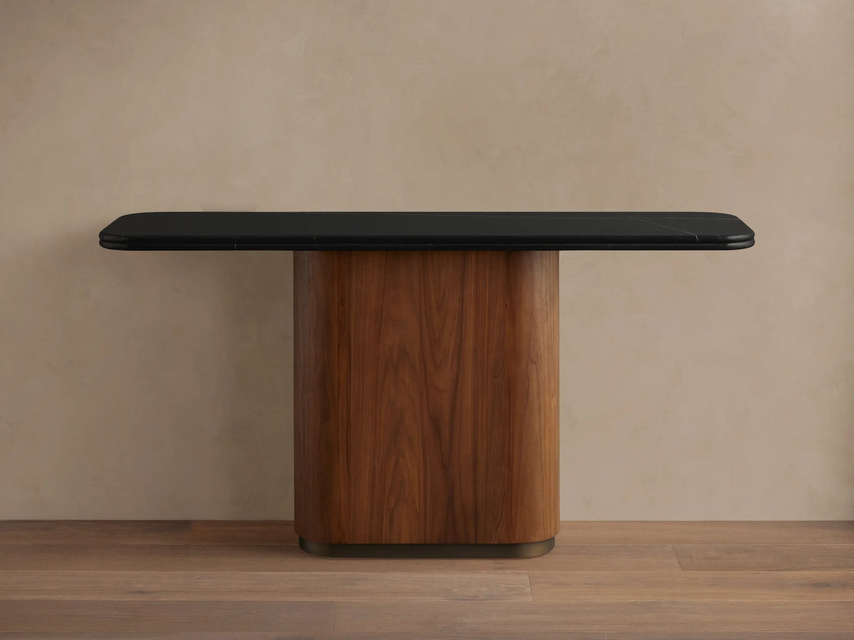 Close-up of a Caden Console Table. Black Marquina stone top with white veining and rounded edge over a walnut wood base.