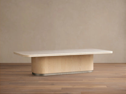 Caden Coffee Table with light cream stone top, sand oak veneer curved base, and brushed nickel plinth on wood floor.
