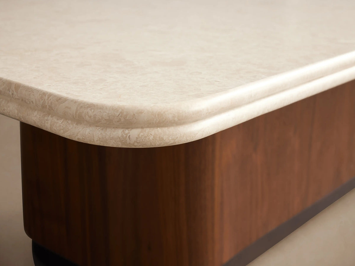 Caden Coffee Table with rectangular cream stone top, rounded corners, solid walnut wood base, and antique bronze plinth.