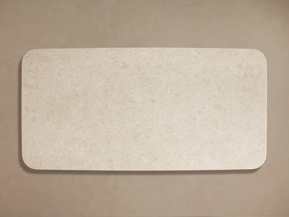 Close-up of Caden Coffee Table. Cream stone top with rounded double-beveled edge rests on a curved dark walnut wood base.