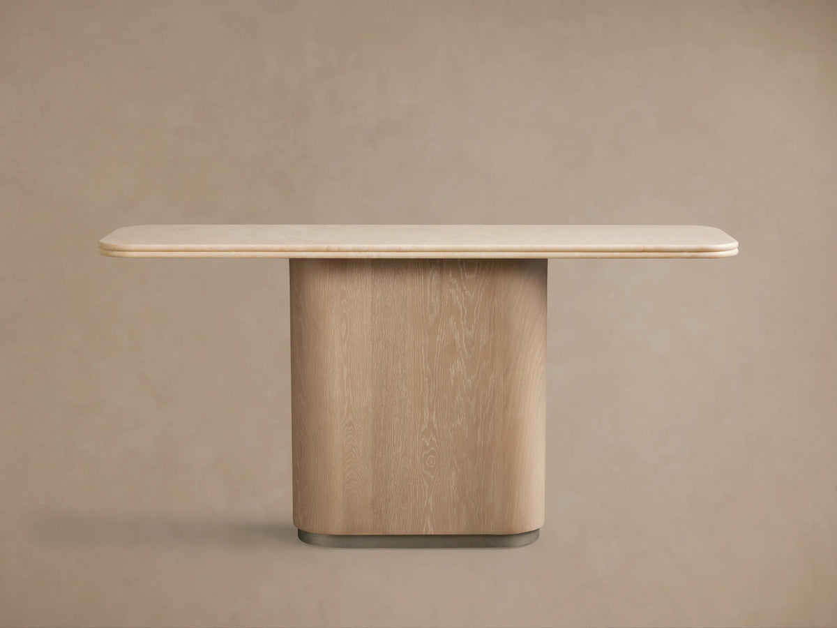 Caden Console Table: sand oak wood veneer base, brushed nickel plinth, cream stone top with rounded edges, in a minimalist room.