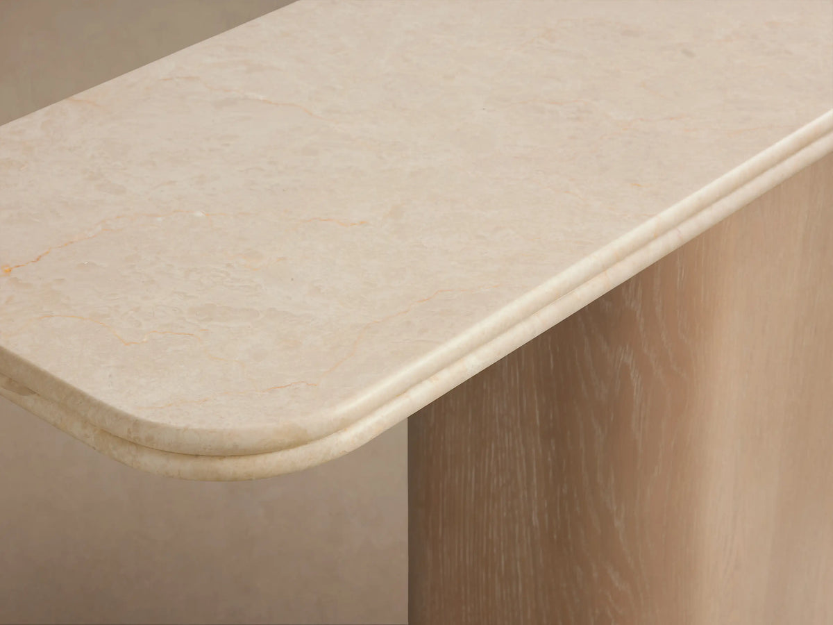 Caden Console Table with a cream stone top on a light sand oak wood veneer pedestal base and a brushed nickel plinth.
