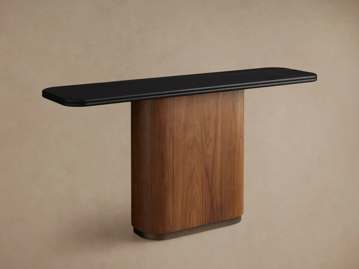 Caden Console Table: black stone top, curved walnut wood veneer base with an antique bronze plinth. Vase & book on top.