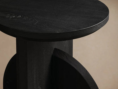 Calderone End Table in matte black finish, featuring a round top and semi-circular base on wooden floor.