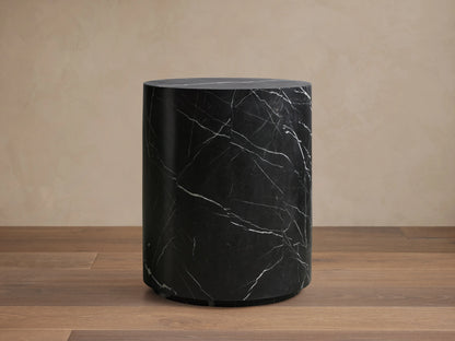 Cylindrical Cinzia Stone End Table made of black marble with white veining, featuring a smooth, polished surface on a wooden floor.