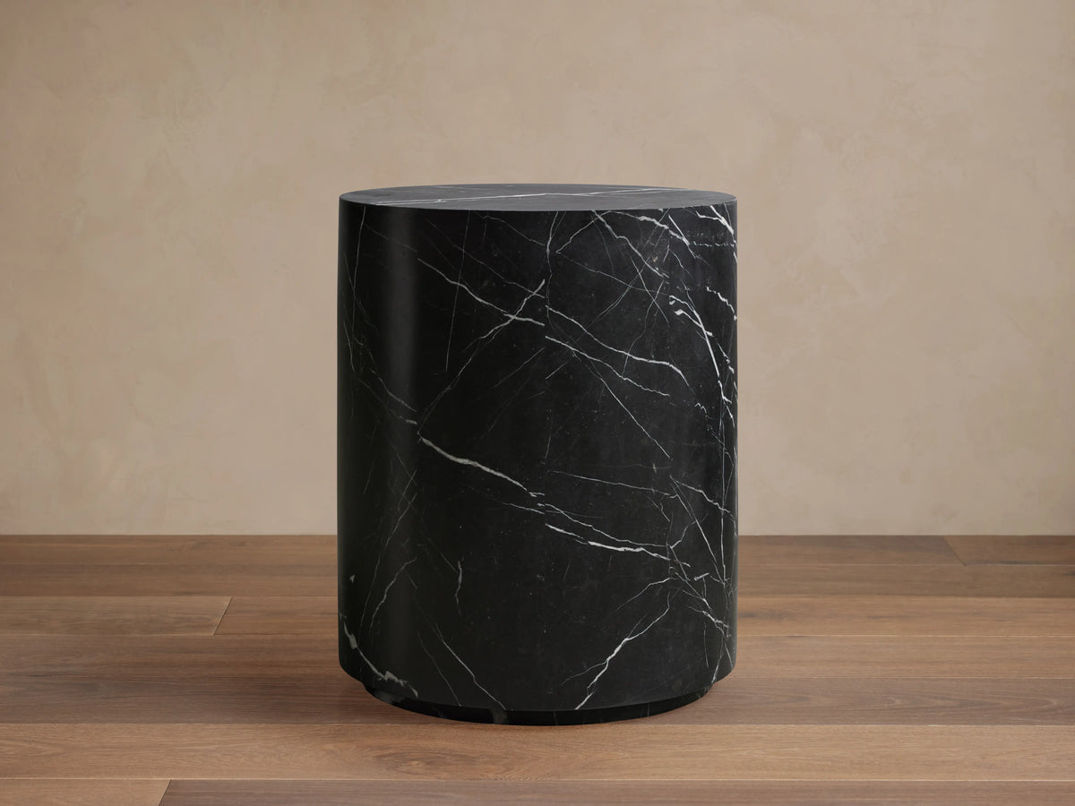 Cinzia Stone End Table with a black marble surface and prominent white veining, featuring a smooth cylindrical shape.